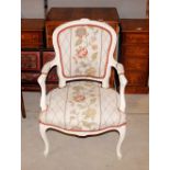 A 19th Century French style cream decorated armchair, having foliate carved decoration, floral linen