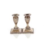 A pair of late Victorian silver dwarf candlesticks, having Campana shaped sconces on square