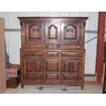 An antique oak court cupboard,  the upper section surmounted by a canopy above fielded panel doors