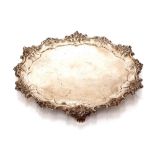 An ornate Edwardian silver salver, having shell and foliate cast borders raised on three pierced and