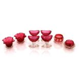 A set of four cranberry and clear glass pedestal salts; a pair of posy vases with flared rims; and