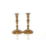 A pair of early / mid 18th Century brass candlesticks, having knopped baluster columns on petal