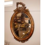 A 19th Century oval gilt framed wall mirror, surmounted by a leaf and ribbon pediment 100cm x 65cm