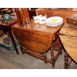 An antique oak gate leg dining table, fitted single end drawer, rounded drop leaves raised on turned