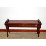 A mahogany window seat, in the Regency style, having rolled ends raised on turned tapering supports,