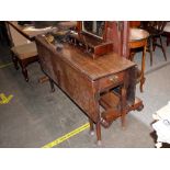 An antique oak drop leaf dining table, fitted end drawers, the rectangular leaves raised on