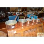 A set of five copper graduated saucepans