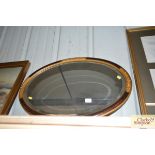 A faux walnut framed bevel edged oval wall mirror