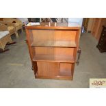 A teak bookcase with glass sliding doors