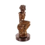 An abstract bronze figure of a boy seated on a roc