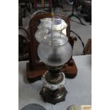 An ornate brass and ceramic oil lamp with etched g