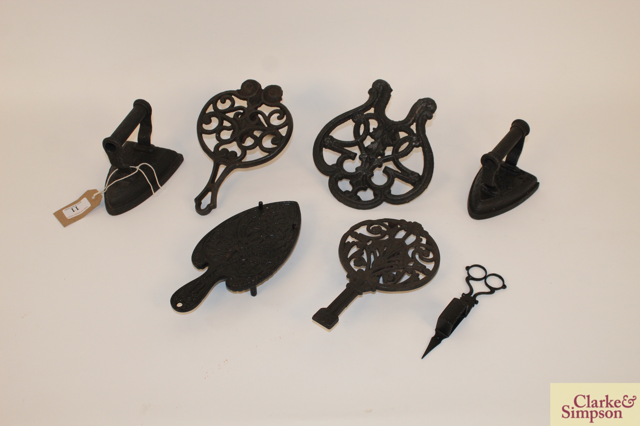 Four various ornate cast iron trivets; two flat ir