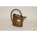 An antique brass watering can with loop handle