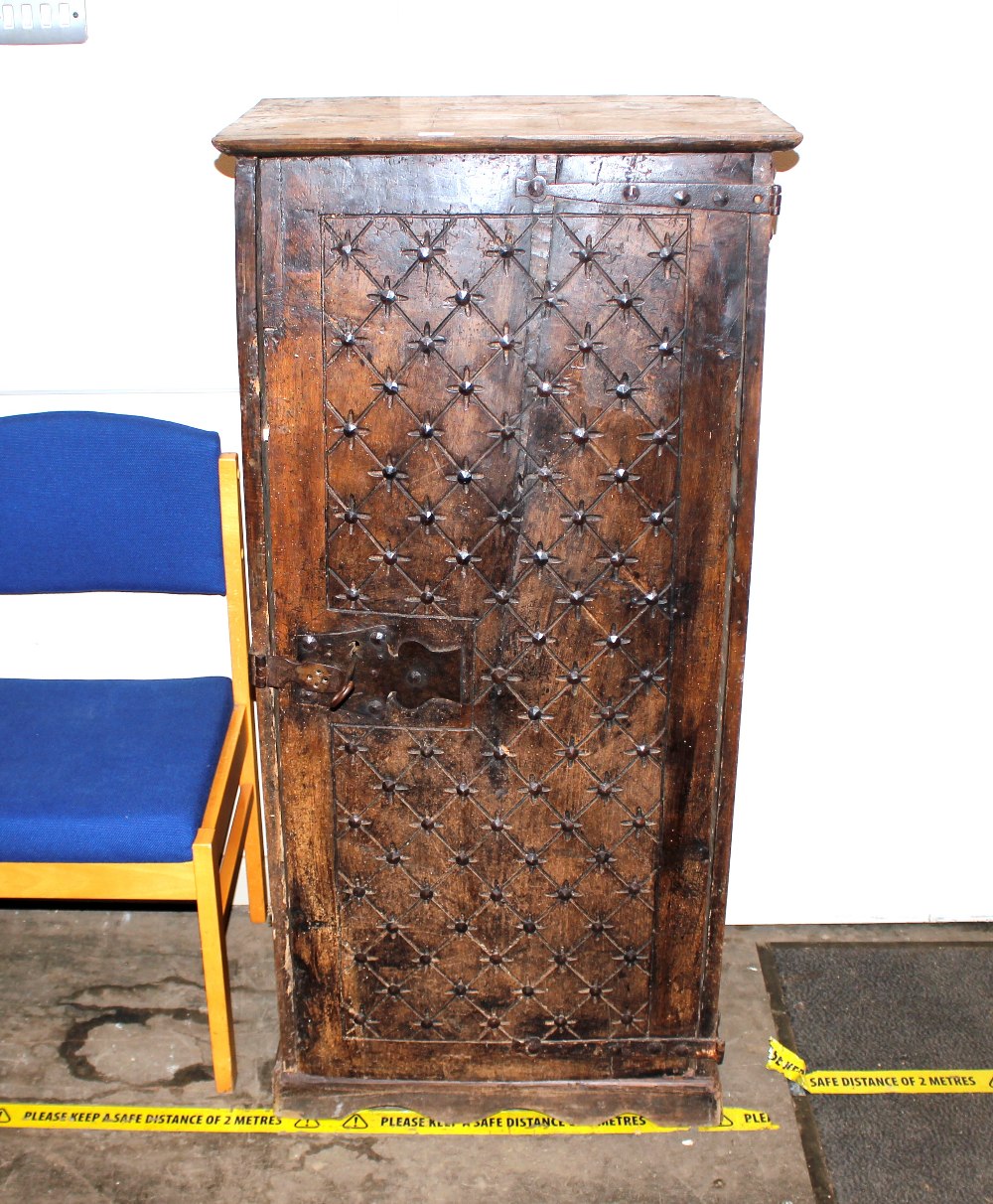 An unusual antique oak narrow storage cupboard, enclosed by a single carved door decorated metal