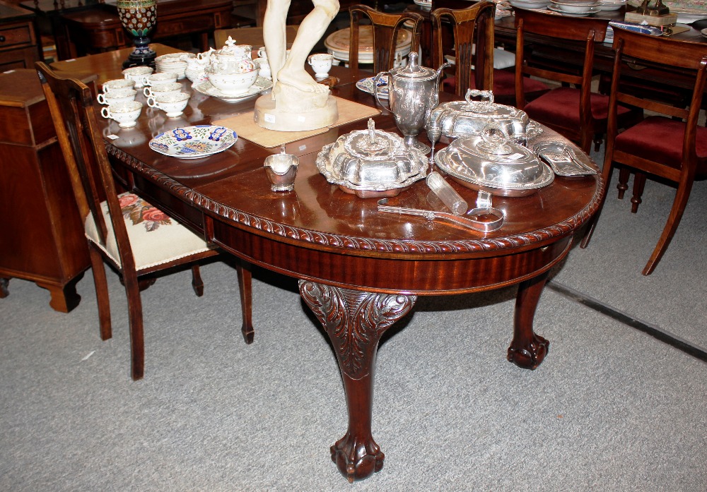 An early 20th Century carved mahogany oval extending dining table, in the Chippendale manner, having