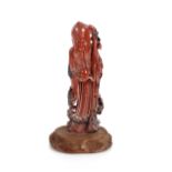 A carved soapstone figure of an immortal, on wooden base, 16.5cm high