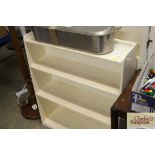 A white painted open fronted bookcase