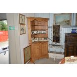 An antique stripped pine corner cupboard