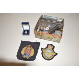 A tin and contents of various cloth badges, button