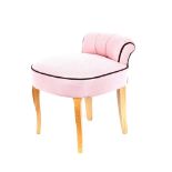 A pink upholstered dressing table chair, raised on