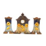 An Art Nouveau pottery clock garniture, having pop