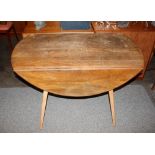 An Ercol drop leaf kitchen dining table, raised on
