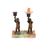 A pair of bronzed cherub candlesticks, raised on s