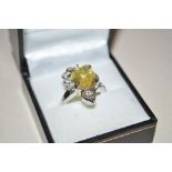 A boxed white metal ring set with yellow stone