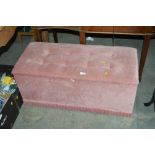 A pink upholstered ottoman