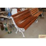 An ornate cast iron and teak slatted roll top benc
