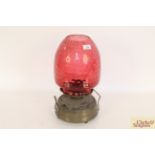 A large brass oil lamp with dimpled ruby glass sha
