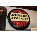 A circular metal "Dunlop Stockist" advertising sign, approx. 24" dia.