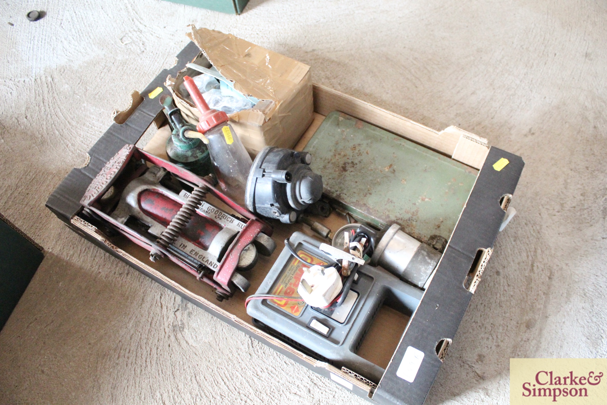 A box containing a vintage foot pump, a battery ch