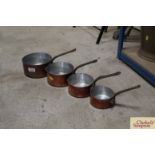 A set of four graduated copper saucepans with iron