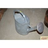 A large galvanised watering can with rose
