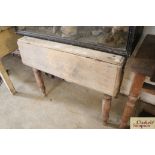 An antique stripped pine drop leaf kitchen table