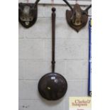 An antique copper warming pan with turned wooden h