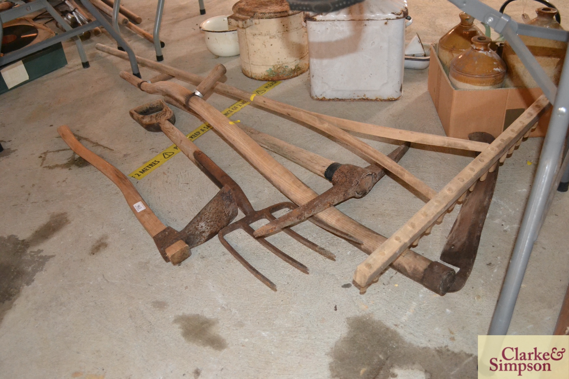 A vintage wooden rake, a scythe, a fork, a pick ax