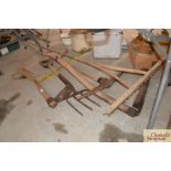 A vintage wooden rake, a scythe, a fork, a pick ax