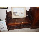 A carved oak bench with under seat storage