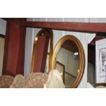 A gilt framed oval bevel edged wall mirror and an