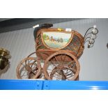 A vintage child's pram with china handles and wooden and metal wheels