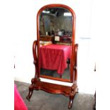 A Victorian mahogany cheval mirror, raised on scrolled arms and shaped base terminating in