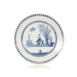 An 18th Century English Delftware blue and white charger, painted with an Oriental figure smoking