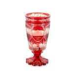 A Bohemian ruby glass goblet, the thumb press panels decorated buildings above a vine etched