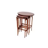 A nest of early 20th Century mahogany occasional tables, having beadwork borders, raised on