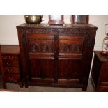 An 18th Century carved oak storage cupboard, the interior shelves enclosed by foliate panelled doors