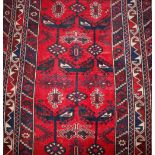 A Middle Eastern wool rug, of Caucasian design having stylised motifs on a brick red ground, 186cm x