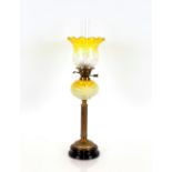 A Victorian oil lamp, with brass Corinthian column and yellow opaque reservoir and tinted shade,