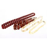 A cherry amber coloured string of graduated beads; another set of amber coloured beads; mother of